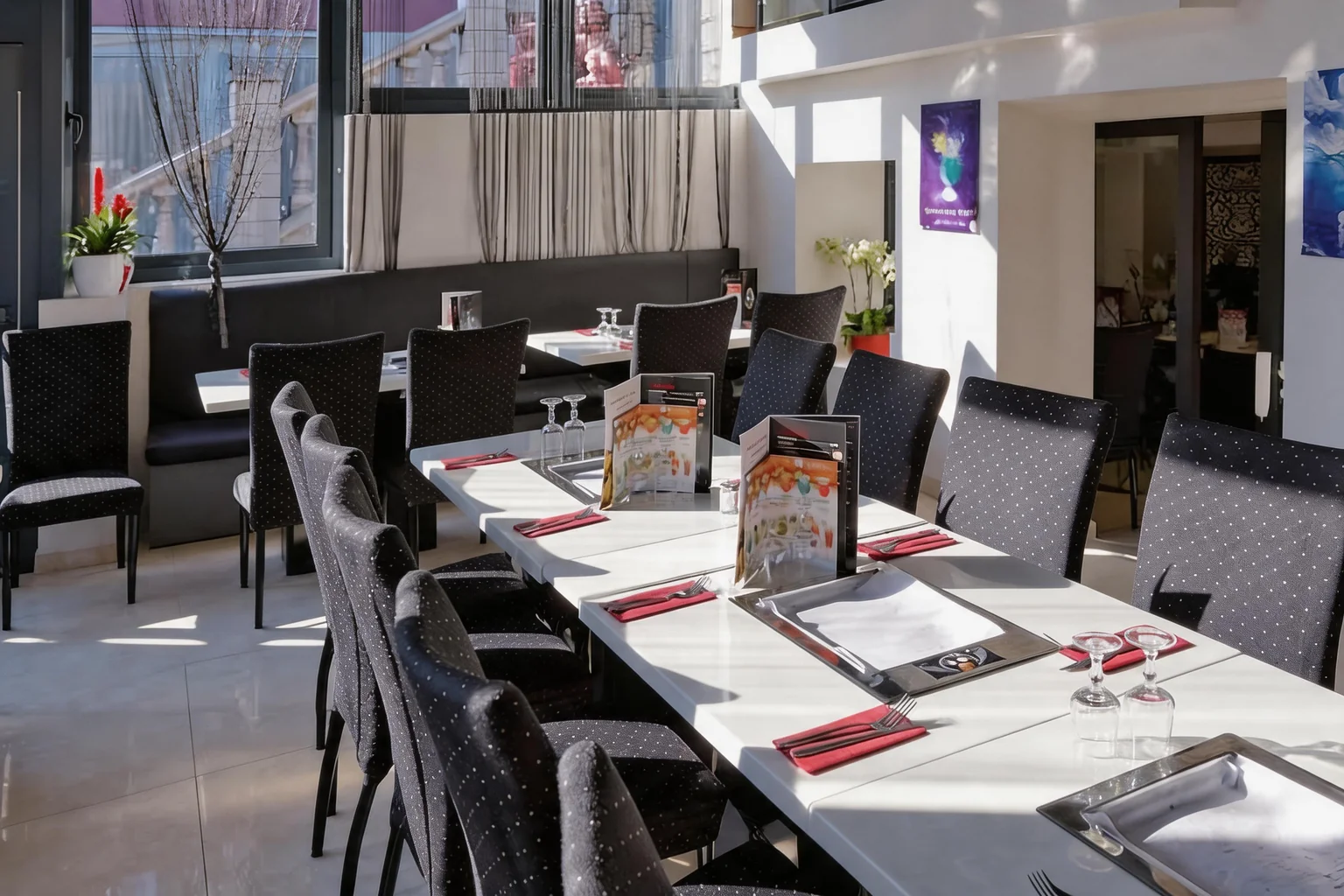 Longue table dressée, chaises noires et serviettes fuchsia