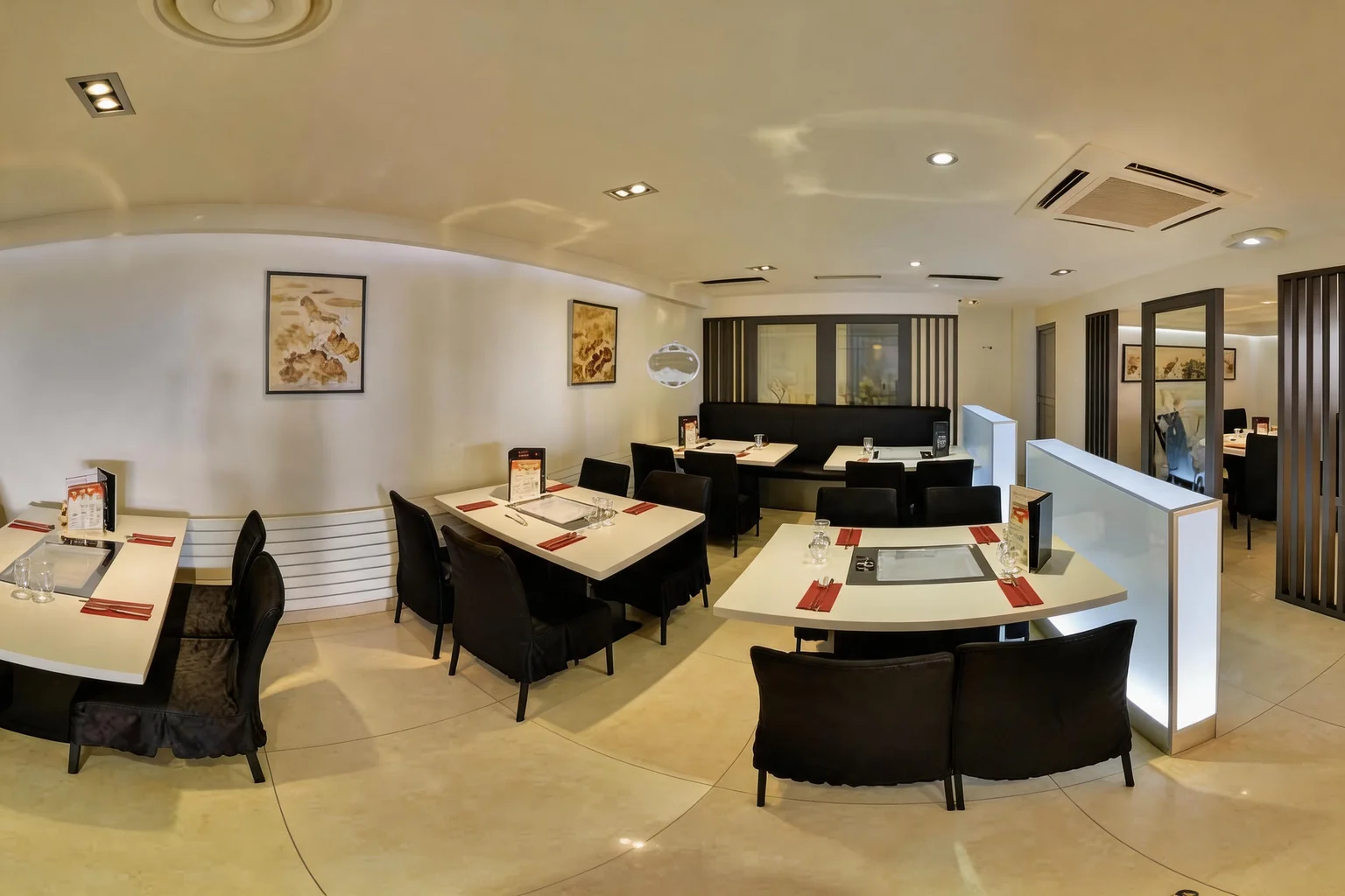 Salle avec tables dressées, chaises noires et tableaux au mur